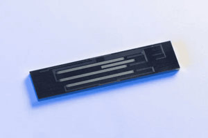Black rectangular electronic sensor with thin metallic lines on a light background.