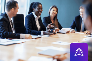 Leadership team sitting at a large board table with closed laptops and paper in front of them on the table