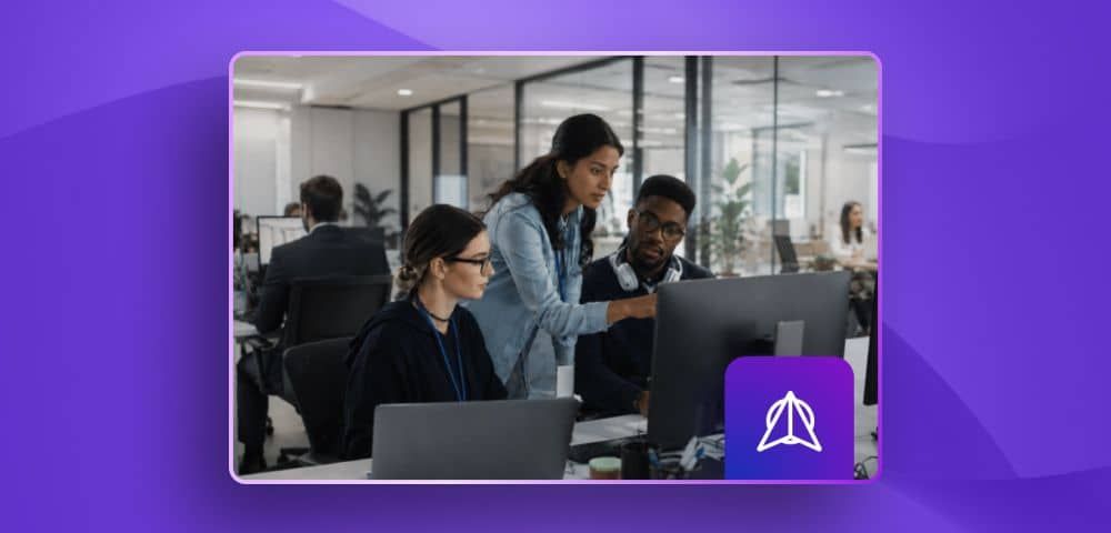 three coworkers looking at a screen collaborating in an office desk
