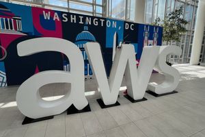 A large white AWS logo sculpture stands in front of a Washington, D.C.-themed backdrop at the AWS Summit venue.