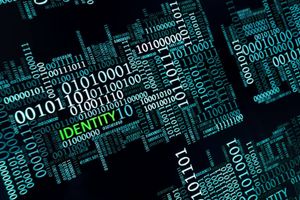 Abstract digital graphic of binary code forming human profile silhouettes, with the word "IDENTITY" highlighted in green, representing digital identity, cybersecurity and identity management.