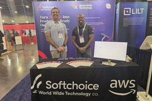 Two WWT and Softchoice team members stand at their AI4 2026 conference booth in front of a backdrop reading 'Turn AI ideas into production-ready outcomes,' with a table draped in a Softchoice, World Wide Technology and AWS branded cloth.