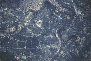 Aerial satellite view of the St. Louis metropolitan area showing the Mississippi and Missouri rivers winding through the city, with a dense network of roads, neighborhoods, industrial zones, and surrounding farmland visible from space.