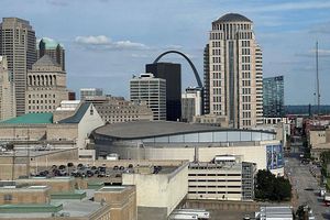 St. Louis skyline featuring the Gateway Arch rising behind downtown office buildings and the Enterprise Center arena in the foreground.
