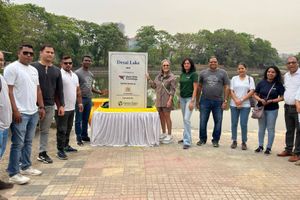 A group of WWT employees and partners stand beside a lakeside plaque dedicating Desai Lake as a 2024 WWT CSR initiative, executed by Green Yatra.
