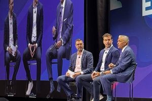 A panel of six business and technology leaders sits on stage during a discussion at VMware Explore 2026, with the event's cloud-logo branding displayed on the screen behind them.