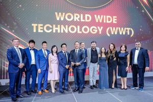 Award recipients pose on stage in front of a large "World Wide Technology (WWT)" display while holding an award during a formal recognition event.