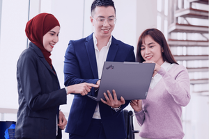 Two women and one men looking at a Thinkpad laptop