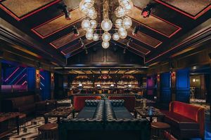 Elegant venue with ambient lighting, featuring leather sofas, a bar, and decorative ceiling lights.