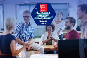 Colleagues gather in an office beneath the Great Place to Work Best Small & Medium Workplaces Europe 2026 logo.