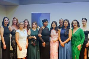 Copilot said:  A group of 11 people pose together in formal attire at an indoor event.