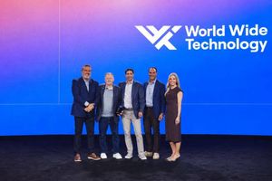 Five people stand together onstage in front of a blue World Wide Technology backdrop, with one person holding an award.