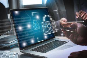 Laptop displaying digital padlocks, symbolizing cybersecurity as people interact with devices.