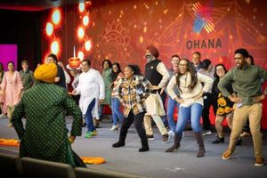 Employees joyfully dancing at an event, OHANA logo in the background.